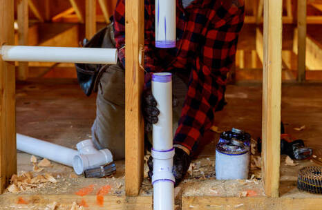 Person installing PVC water pipes in a Norwalk, CT basement.